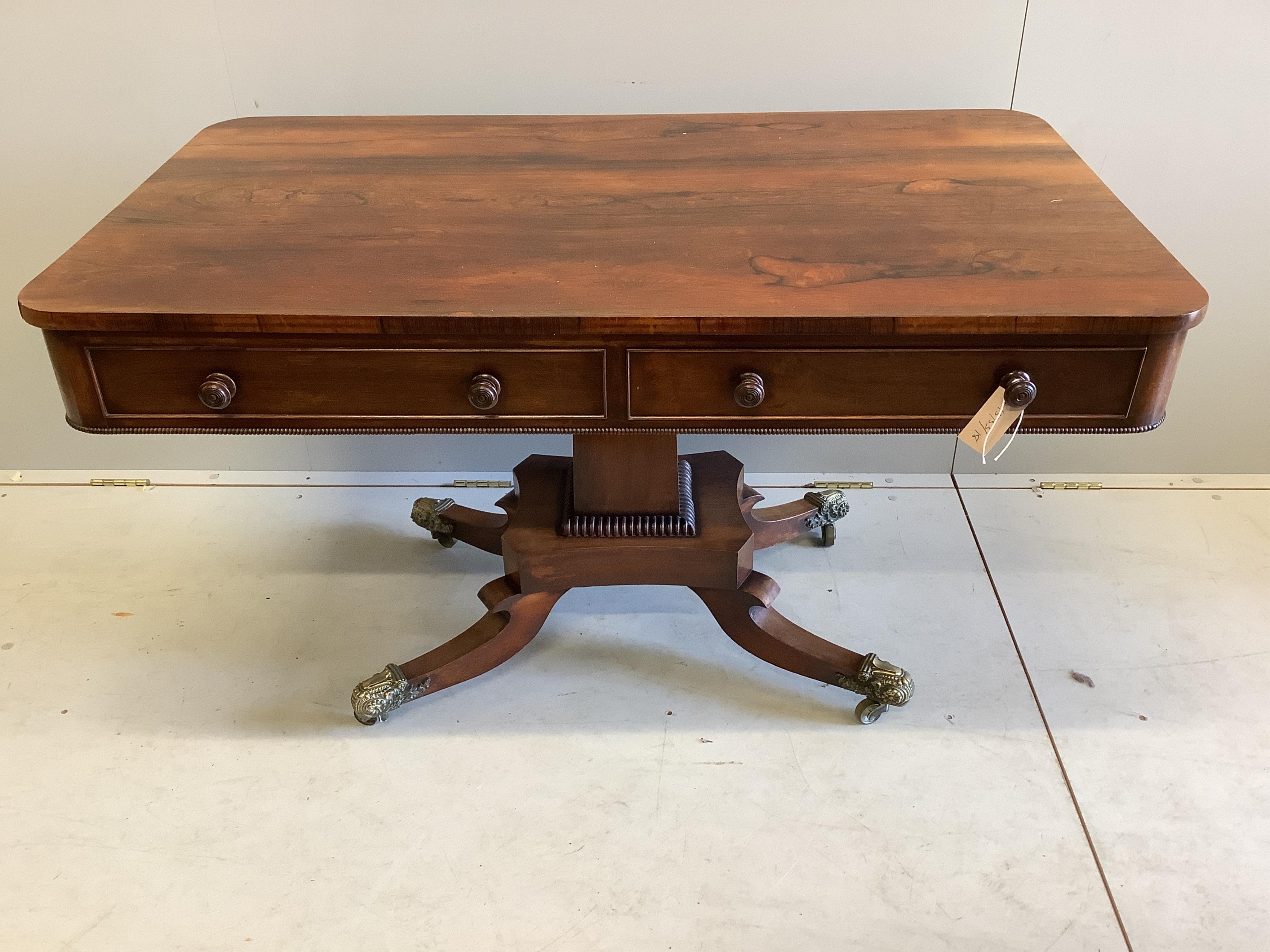 A Regency rectangular rosewood centre / library table, fitted two frieze drawers and two dummy drawers on single square tapered support, quadrapartite slab base and splayed legs with brass castors, width 123cm, depth 70c